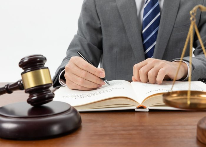 closeup-shot-person-writing-book-with-gavel-table